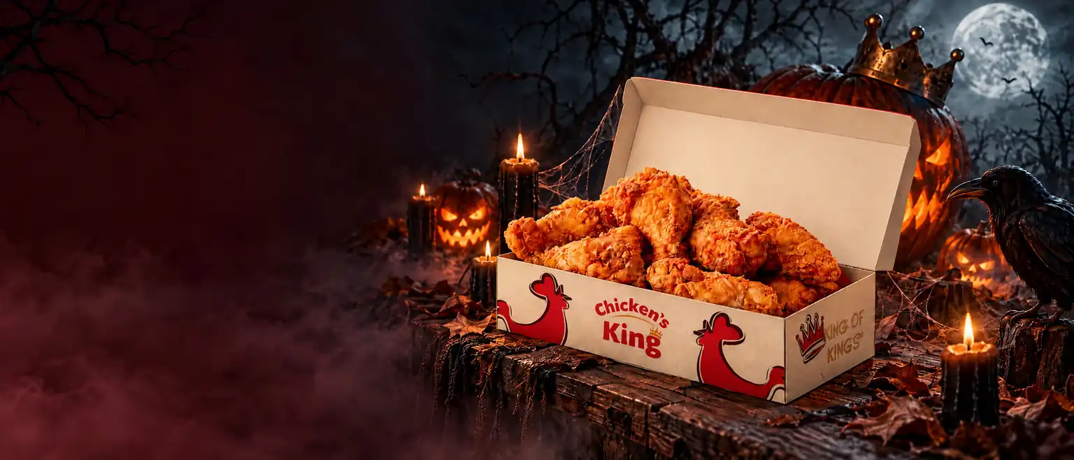 Une box de poulet frit Chicken's King entre des citrouilles, des bougies et un corbeau, sous la pleine lune